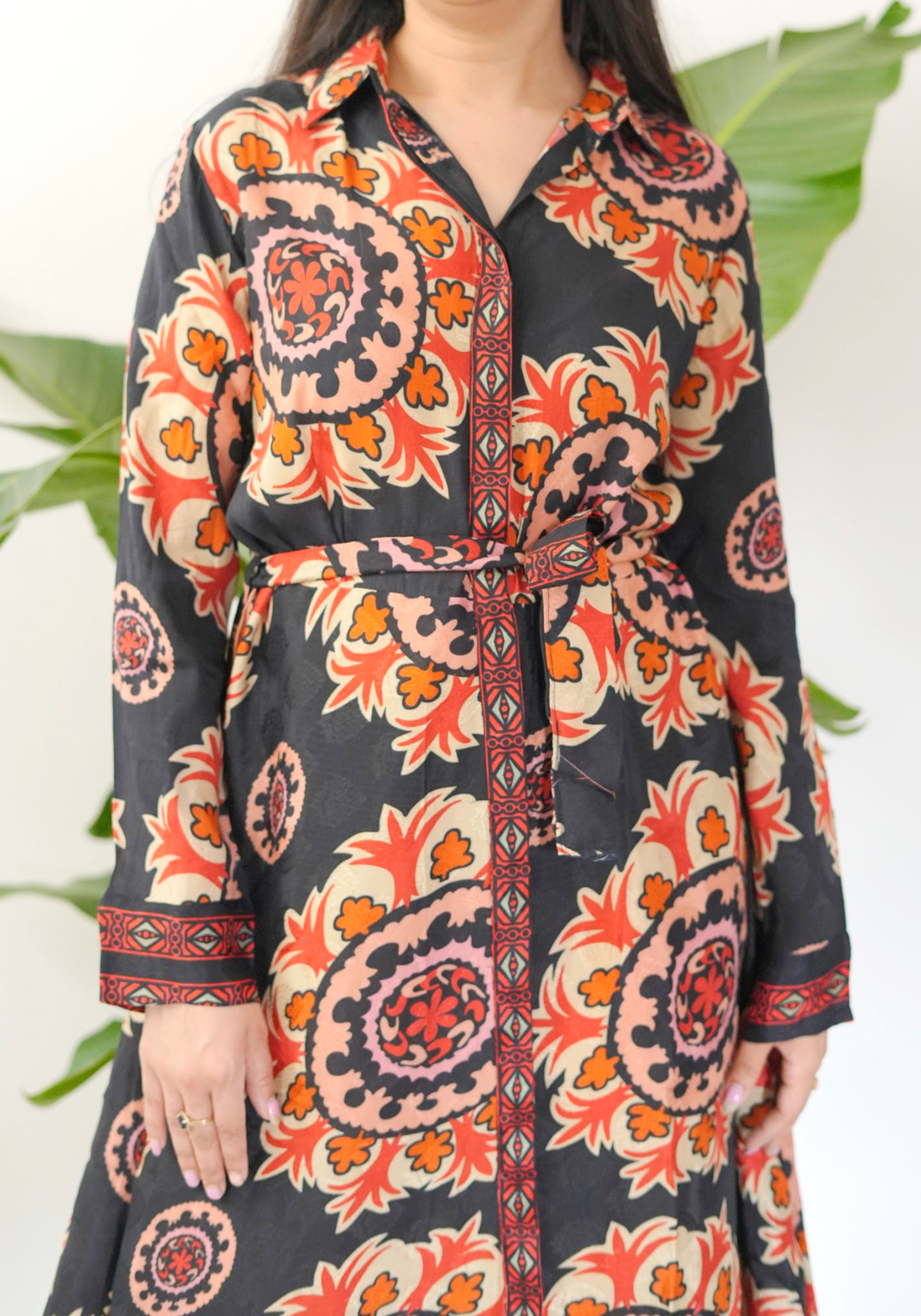Woman wearing a black dress with orange and red floral patterns.