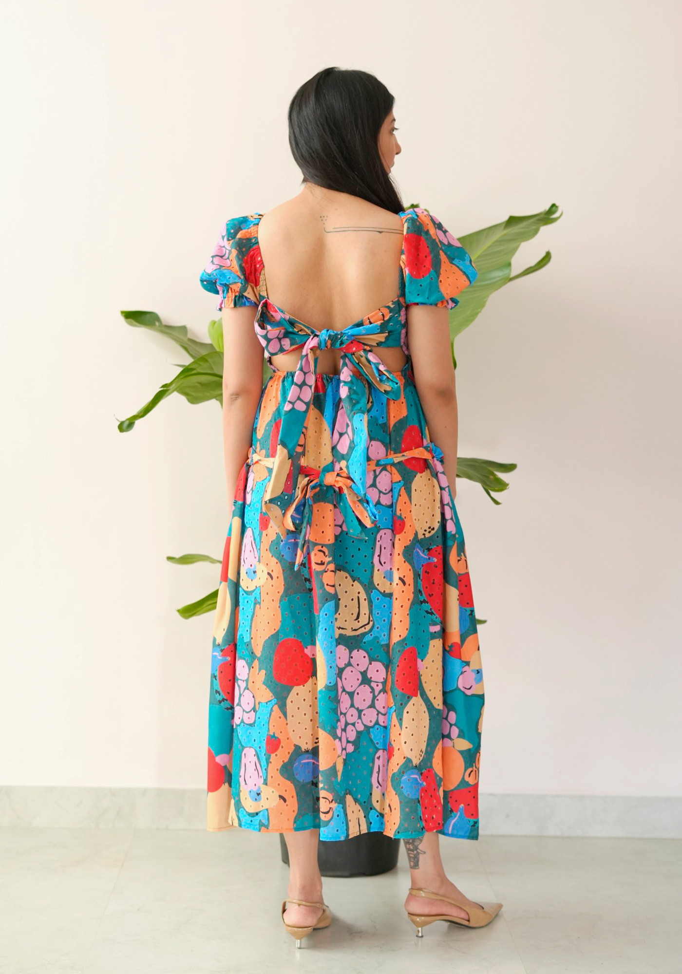 Woman in a colorful dress standing with back to the camera.