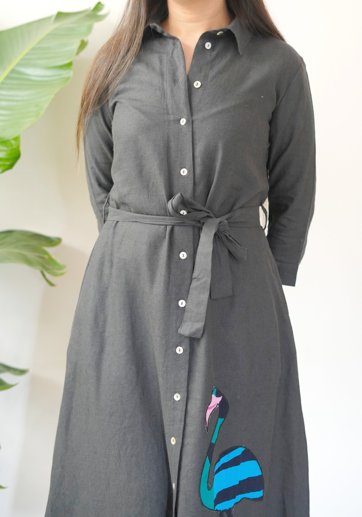 Gray dress with swan design in front of green plants.