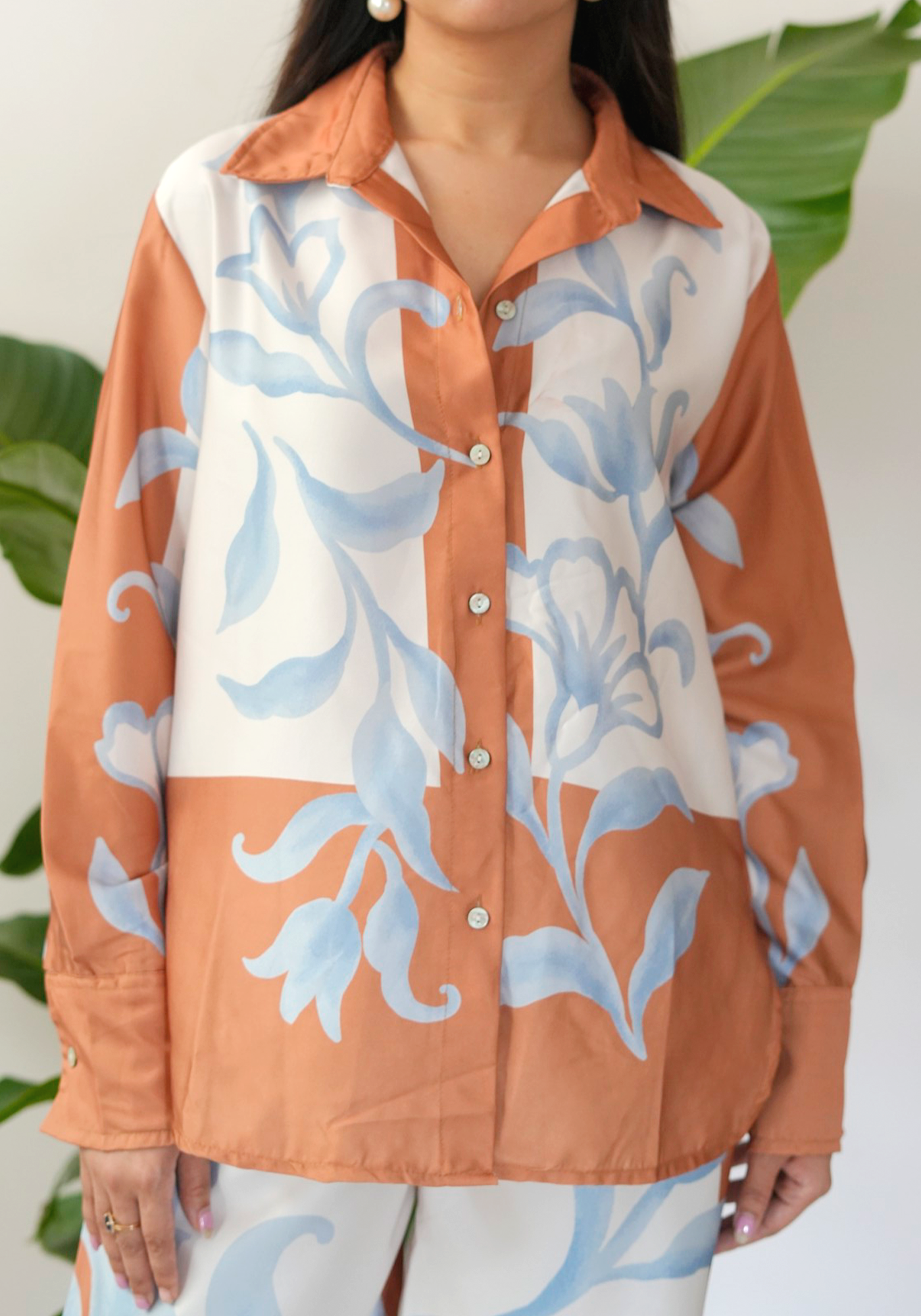 Woman wearing a floral patterned shirt with blue and peach colors.