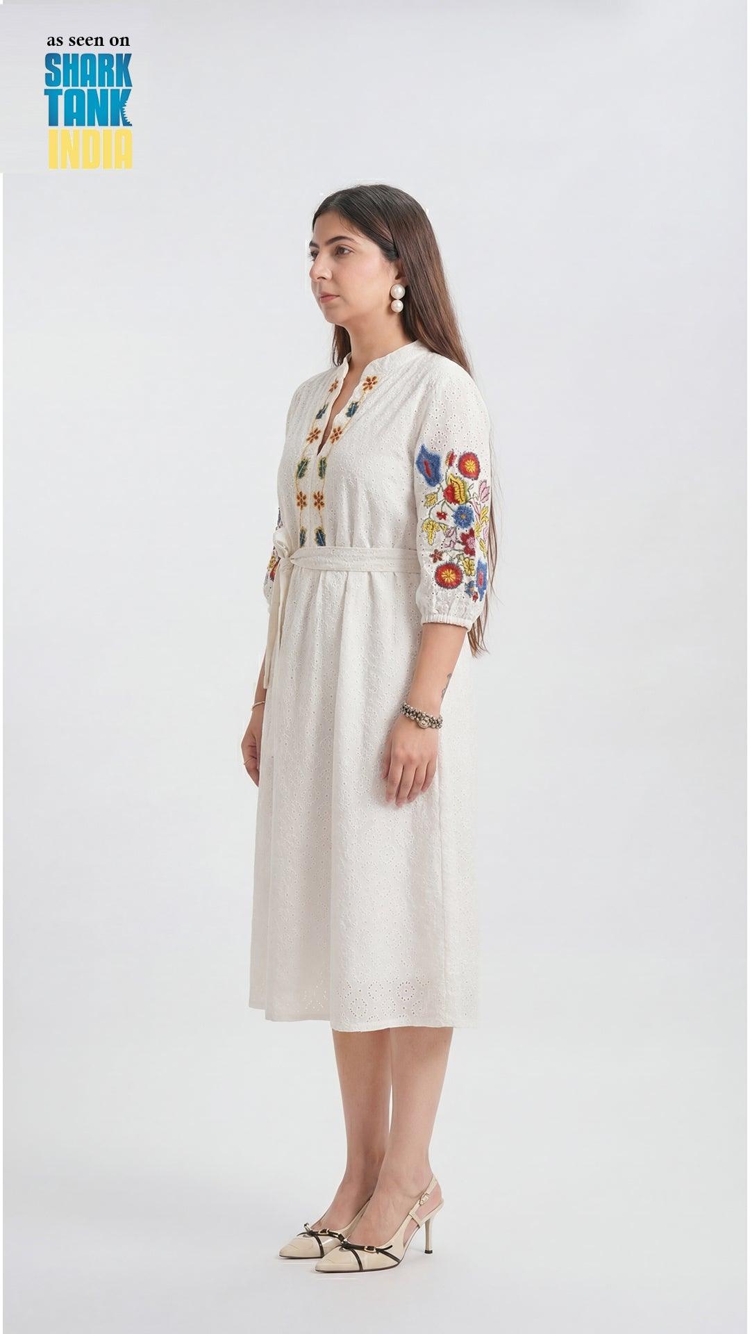 Woman wearing a white dress with floral embroidery on a white background