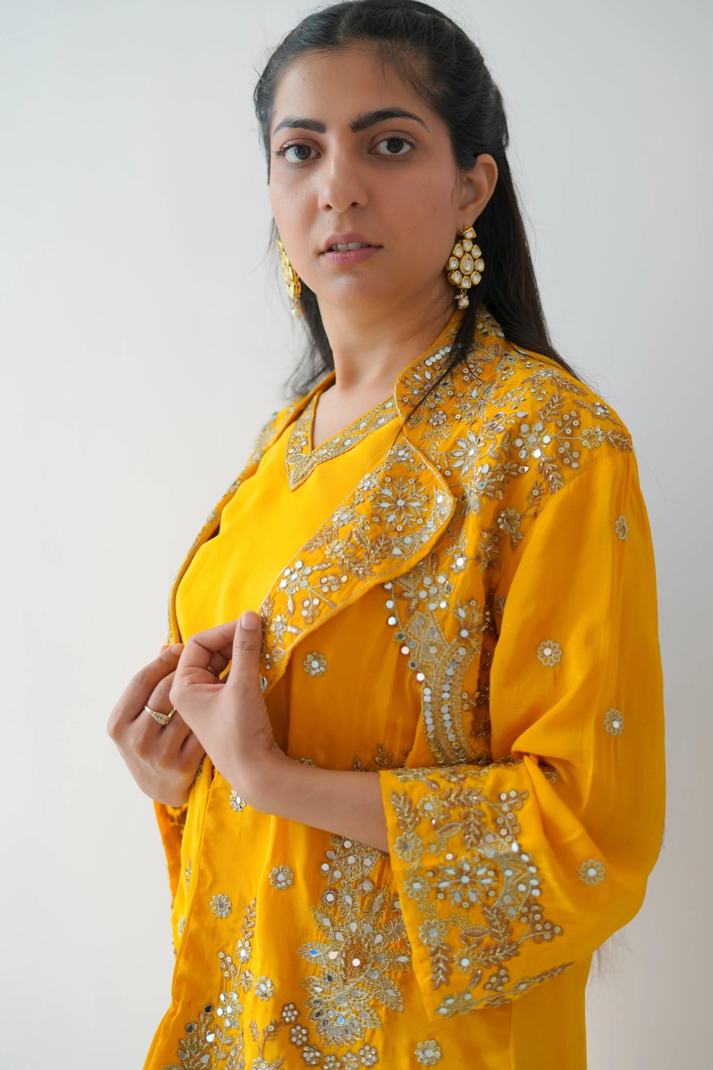 Woman wearing a yellow traditional outfit with intricate designs on a white background