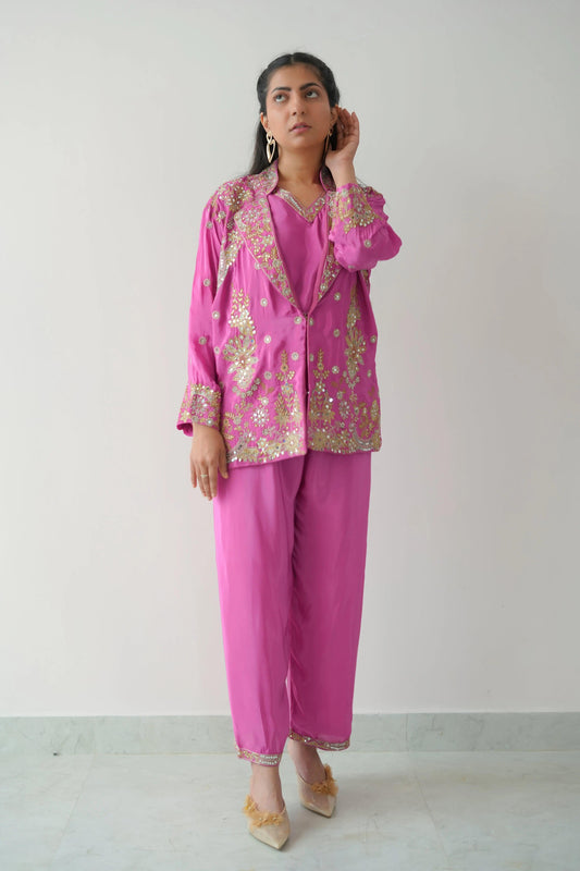 Woman wearing a pink traditional outfit with gold embroidery on a white background
