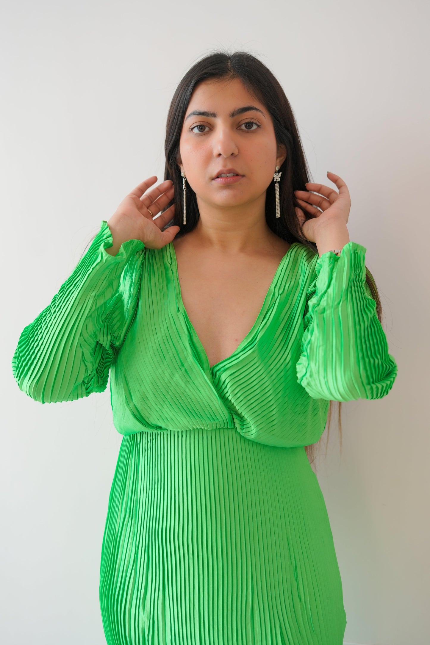 Woman wearing a green pleated dress against a white background