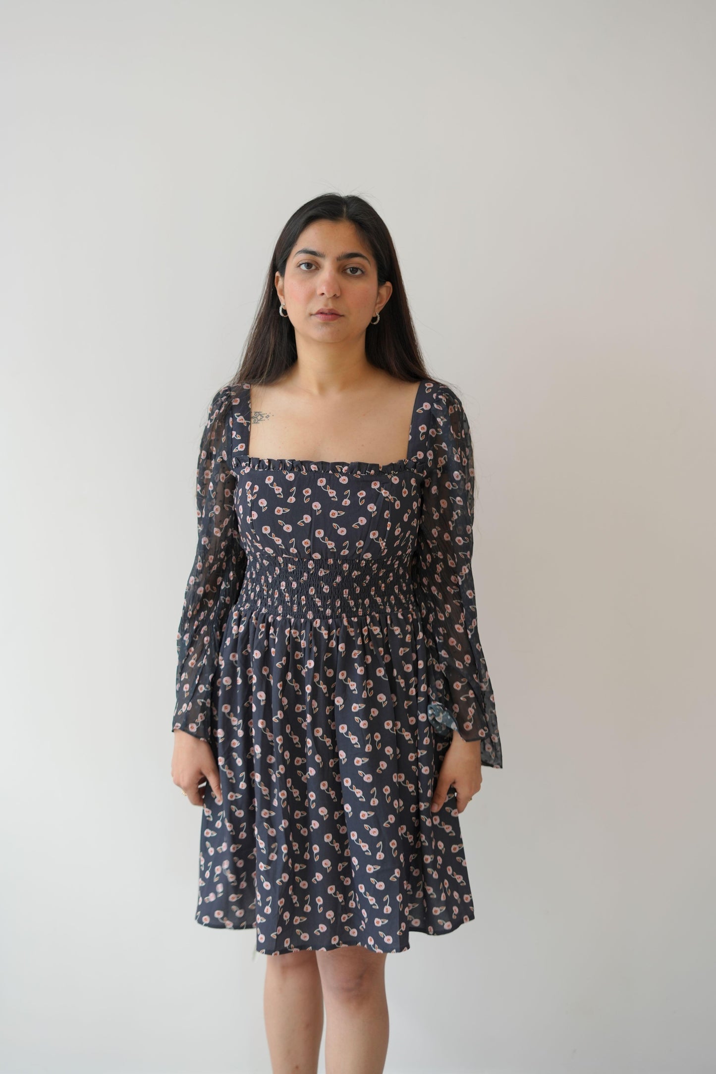 Woman wearing a dark floral dress against a plain background