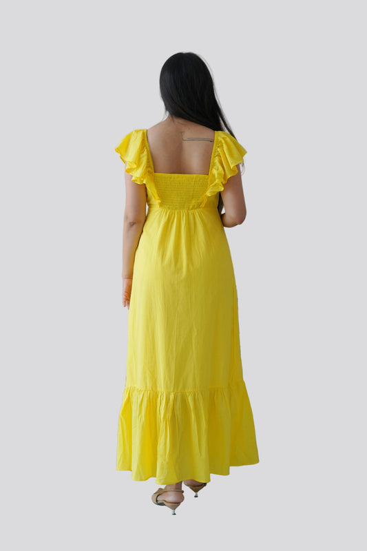 Woman wearing a yellow dress with ruffled sleeves on a light gray background