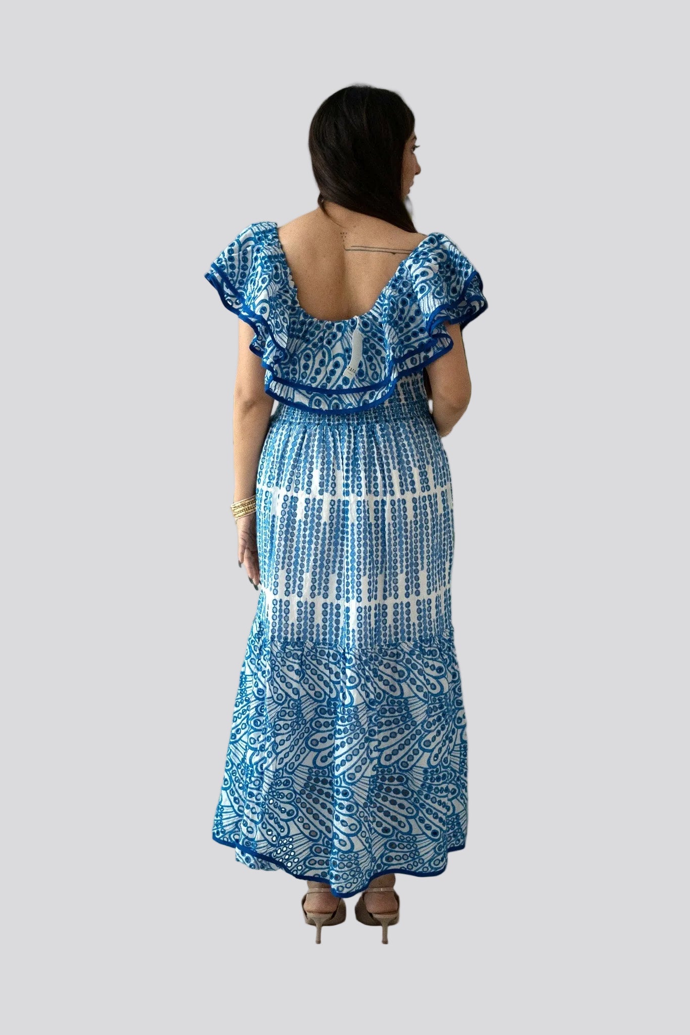 Woman wearing a blue and white patterned dress on a plain background