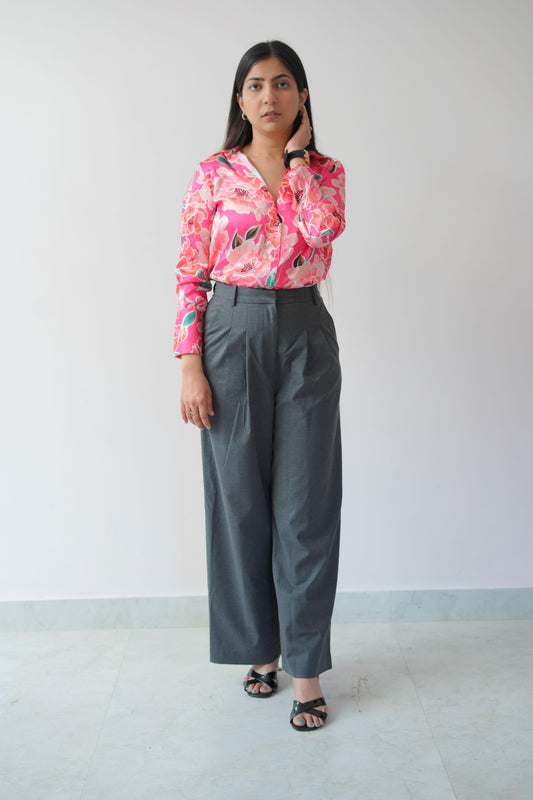 Woman wearing a pink floral blouse and gray pants against a white background