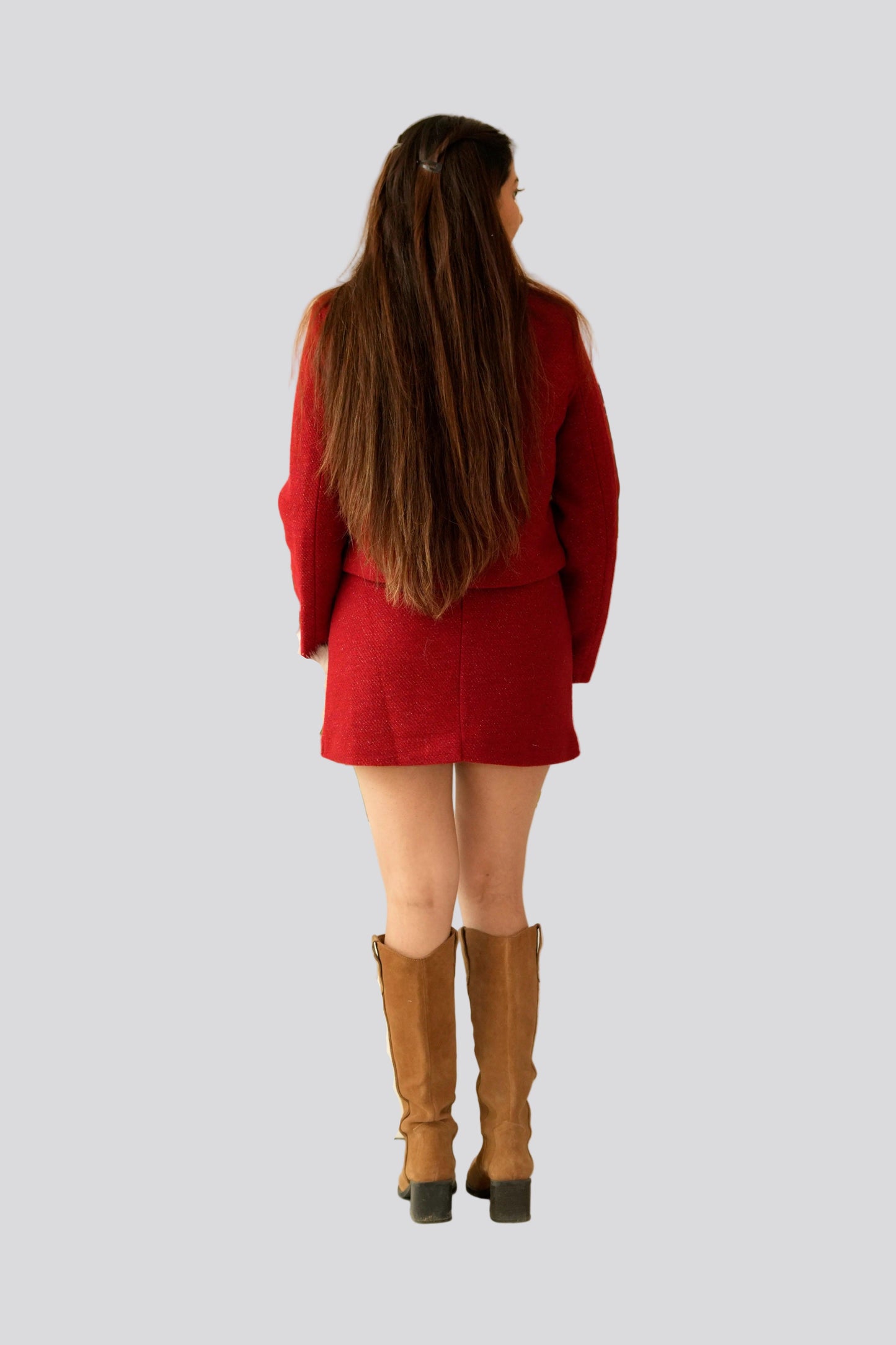 Person wearing a red outfit with brown boots on a light gray background