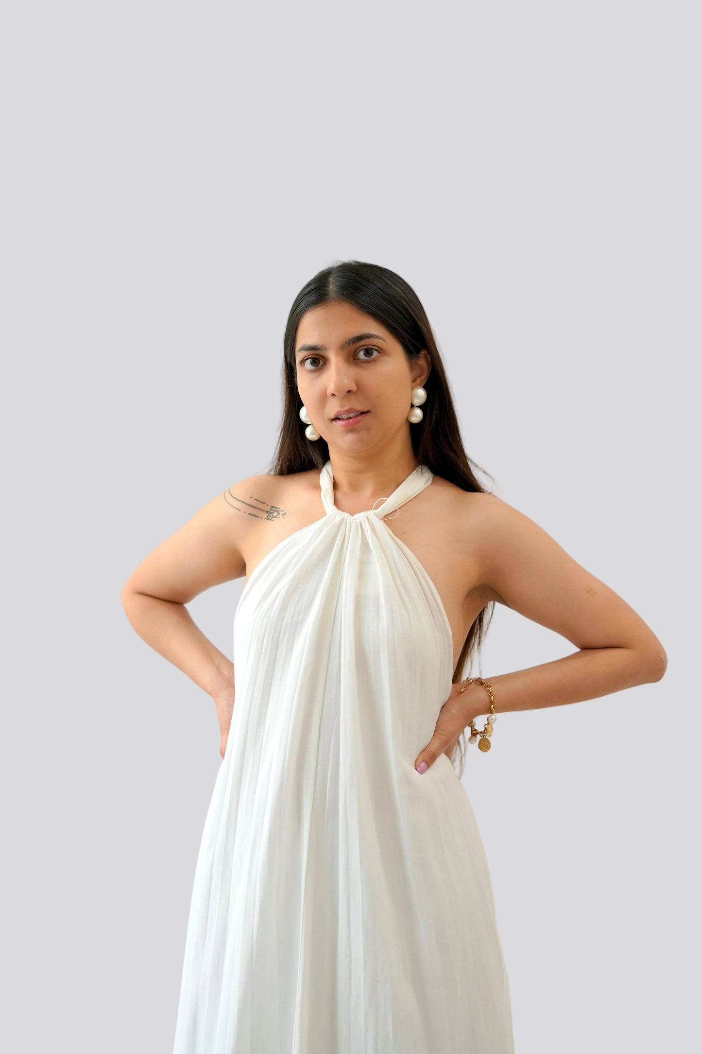 Woman wearing a white halter neck dress on a light gray background