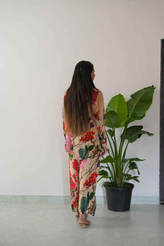 Person wearing a floral dress standing next to a potted plant on a white floor.