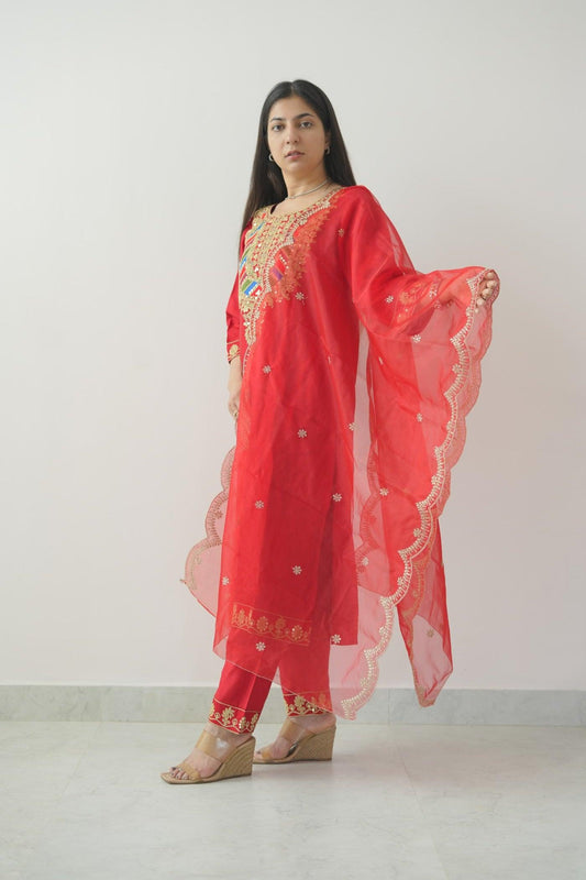 Woman wearing a red traditional outfit with gold embroidery against a white background