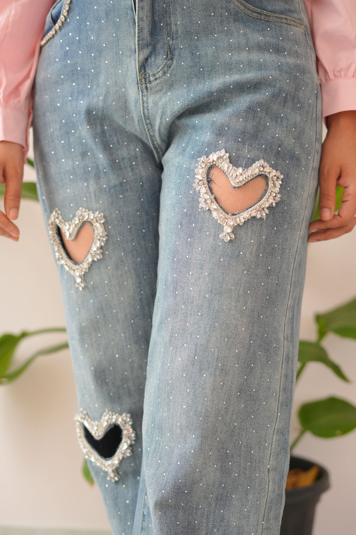 Close-up of distressed blue jeans with decorative heart patches.