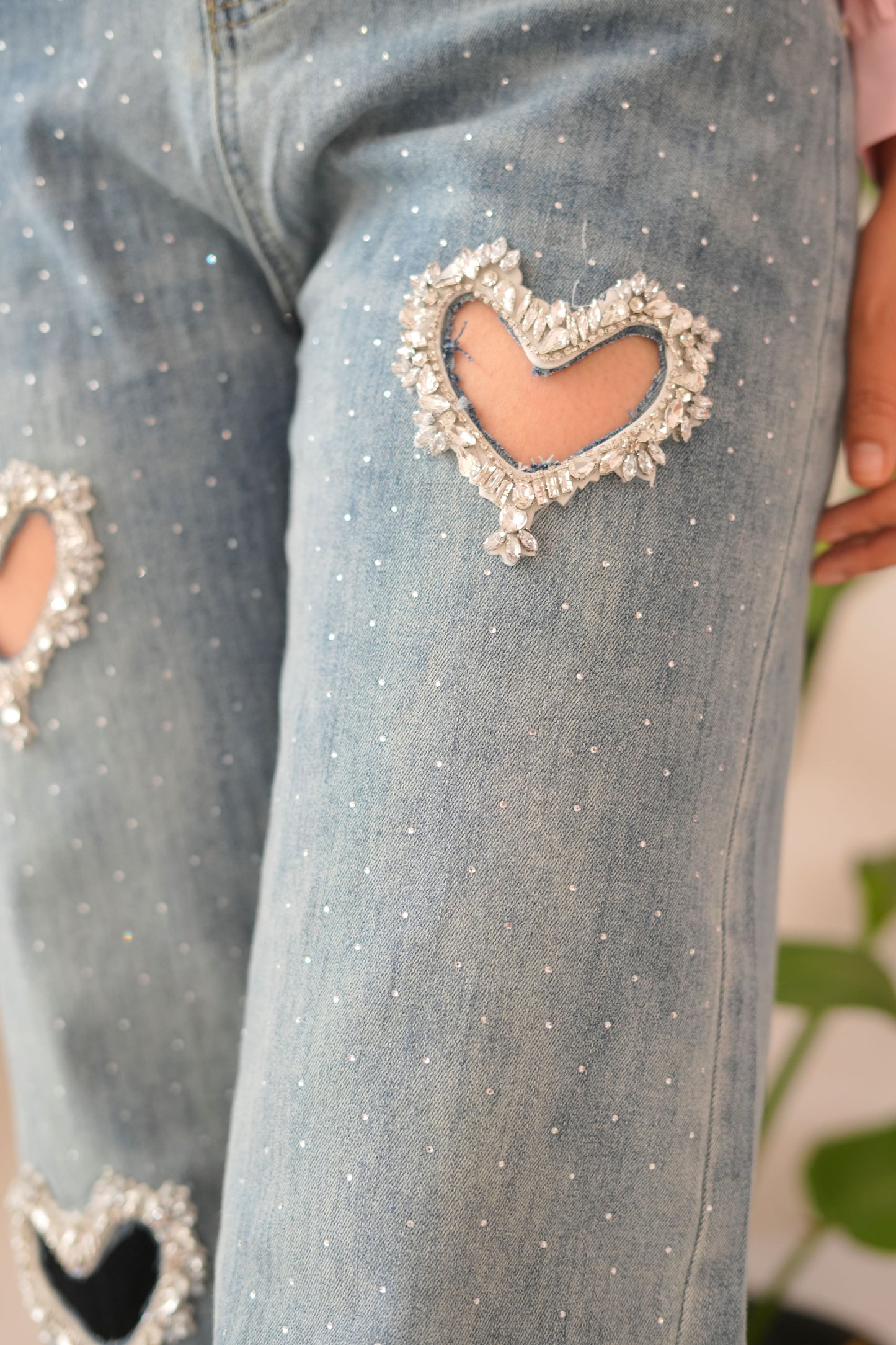 Blue jeans with decorative heart-shaped embellishments on a blurred background