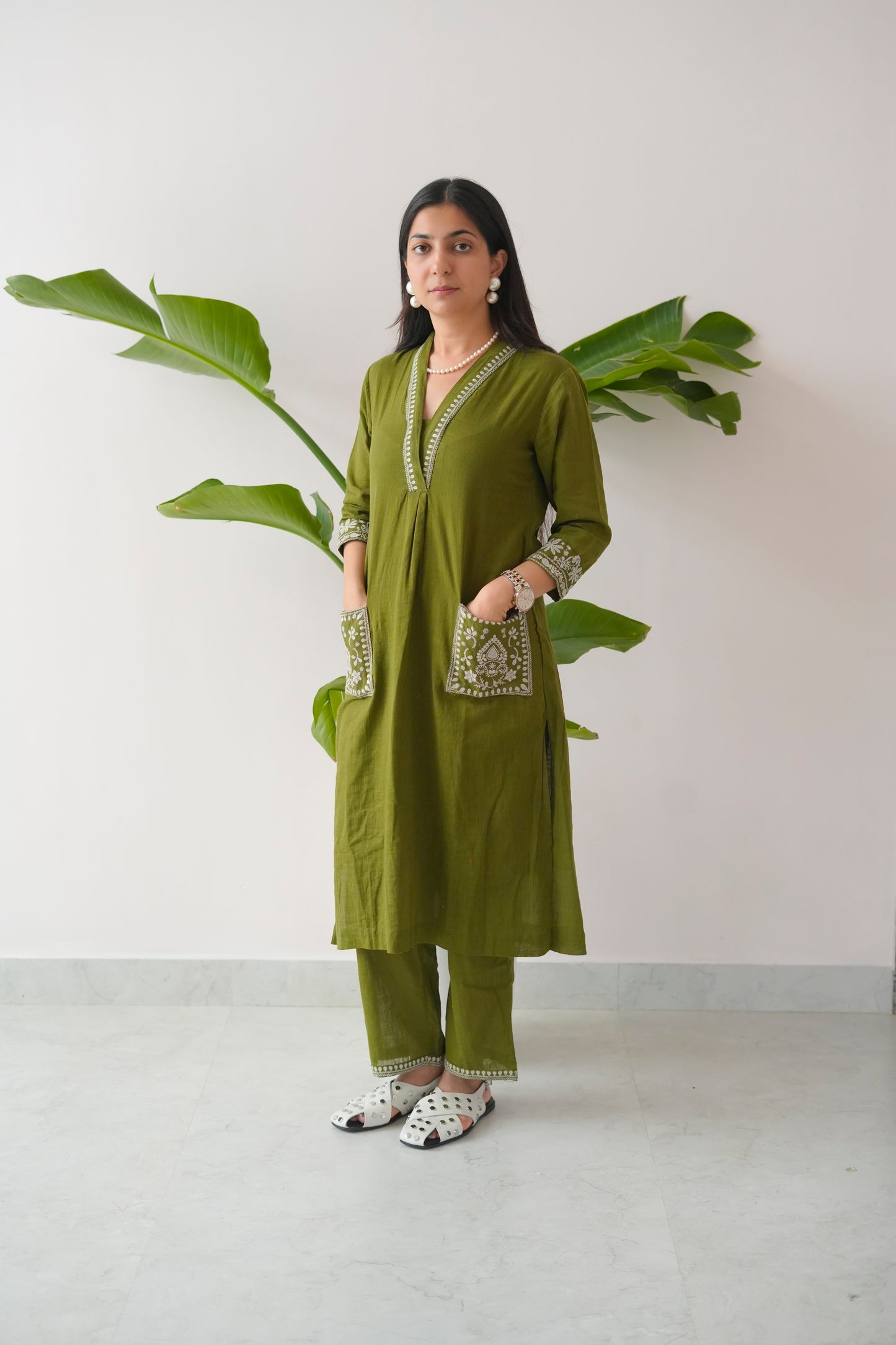 Woman wearing a green traditional outfit with a plant in the background