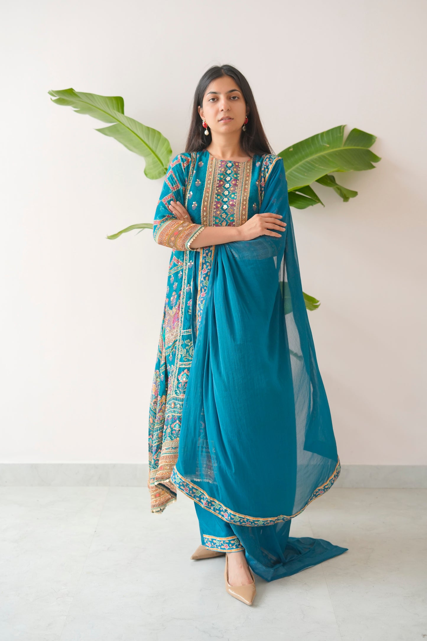 Woman wearing a blue traditional outfit with a white background and green leaves.