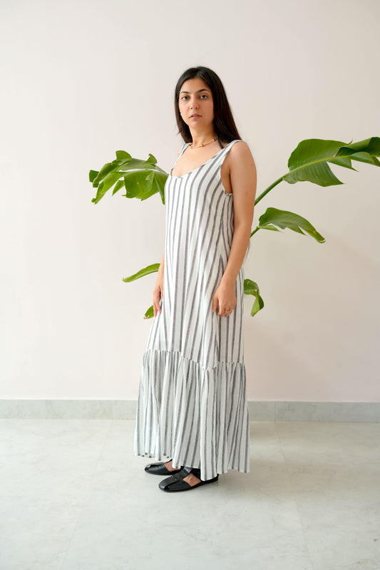 Woman wearing a black and white striped dress standing in front of a plant.