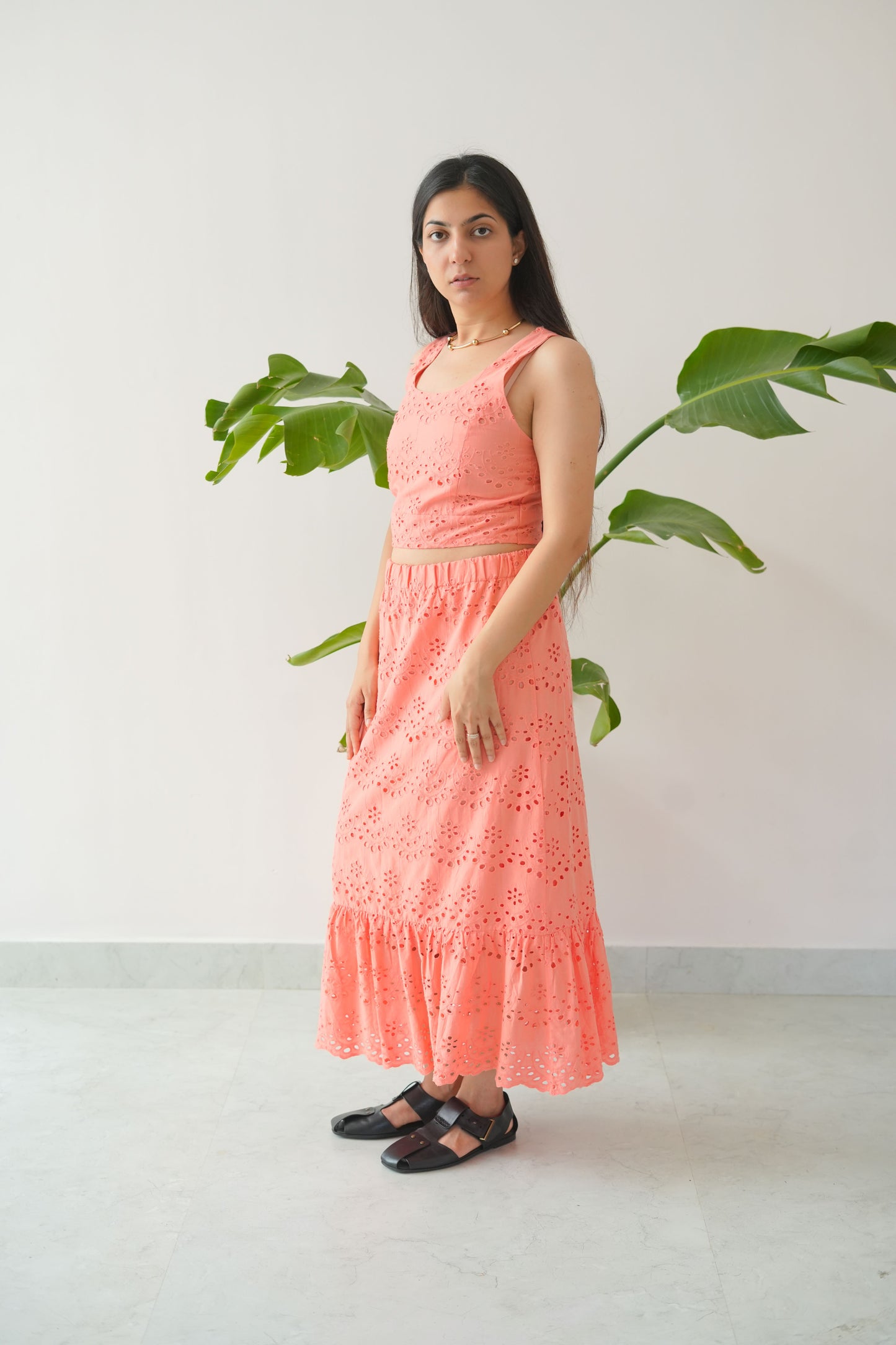 Woman in a pink dress standing next to a plant on a white background
