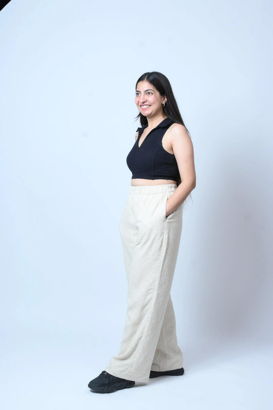 Woman wearing a black top and white pants on a white background