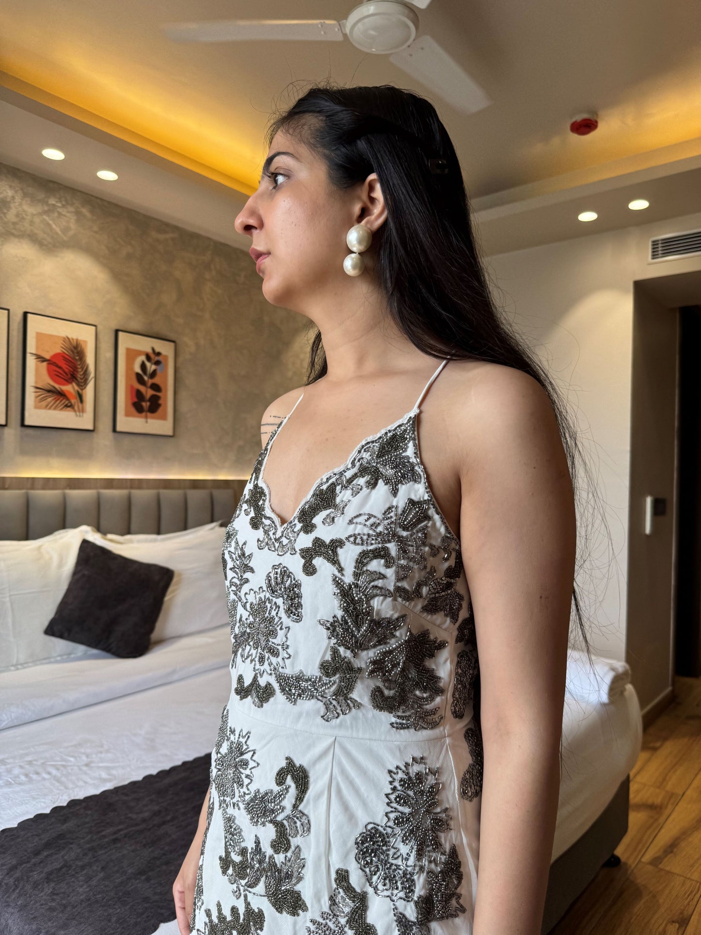 Woman in a white and black floral dress standing in a bedroom.