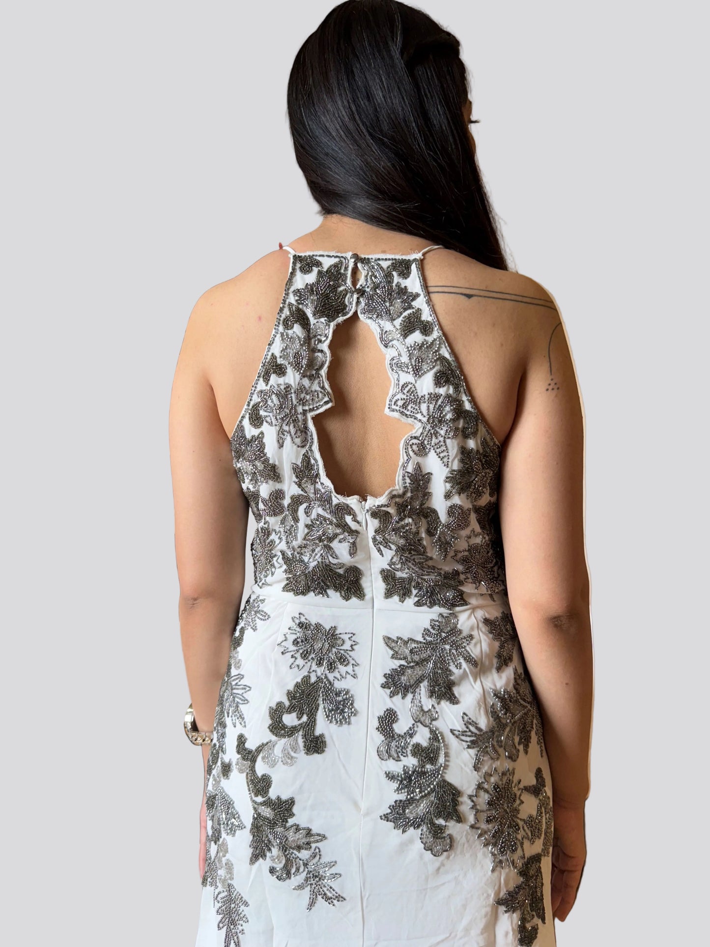 Woman wearing a floral dress with a cut-out back design on a plain background