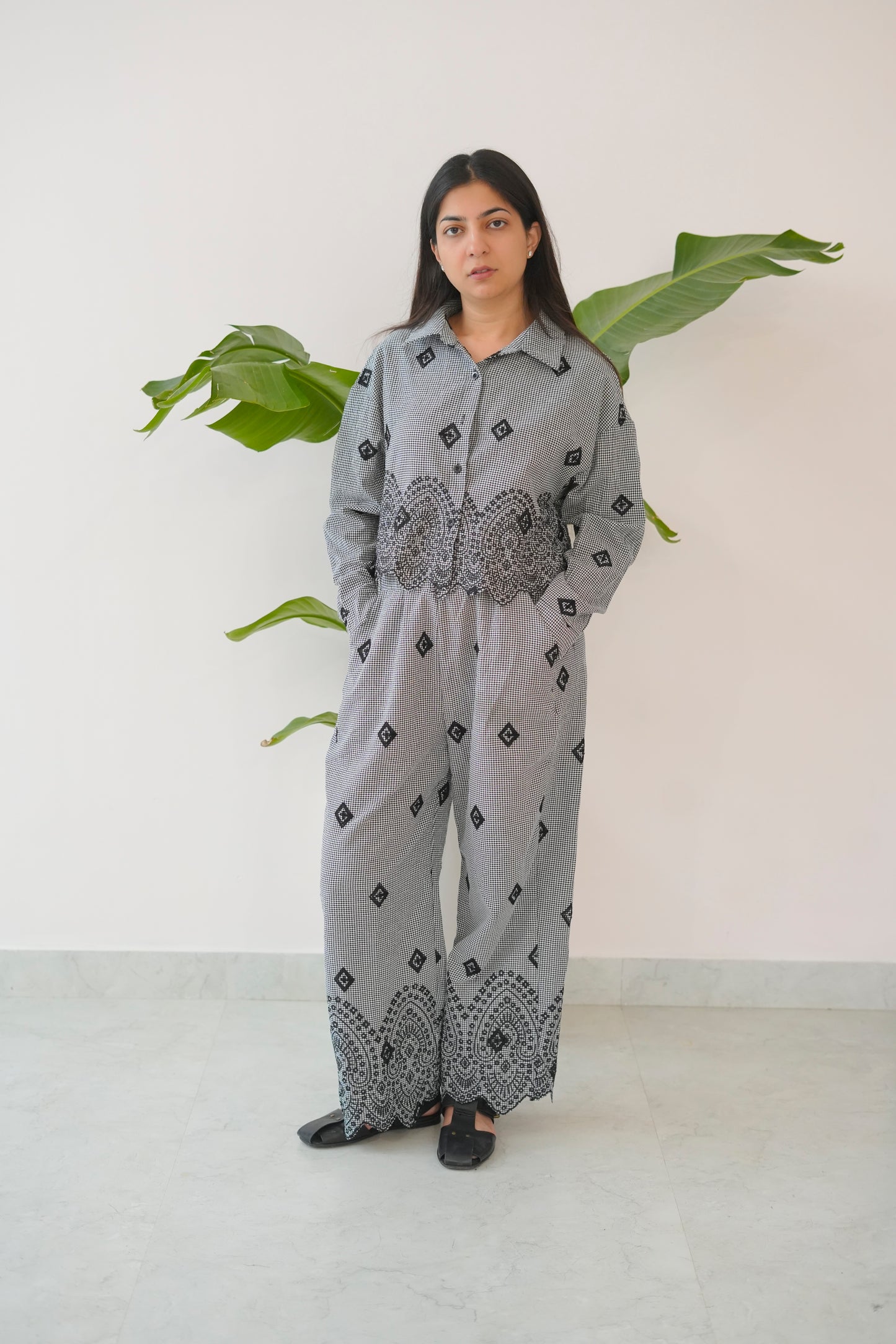 Woman wearing a gray outfit with black patterns in a minimal indoor setting