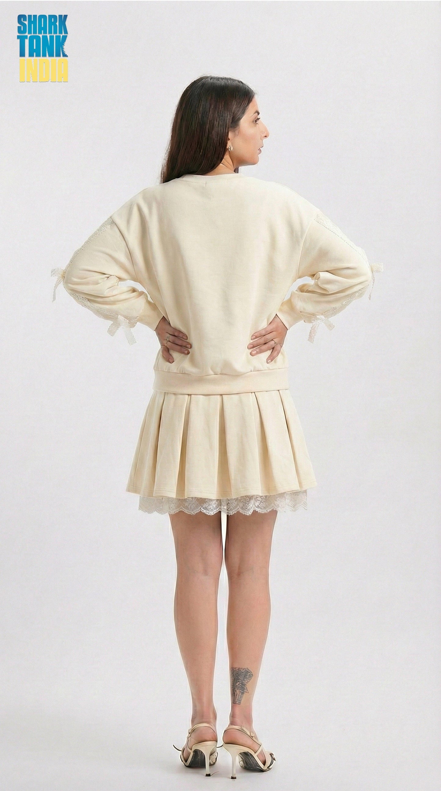 Woman wearing a cream-colored outfit with a skirt on a white background