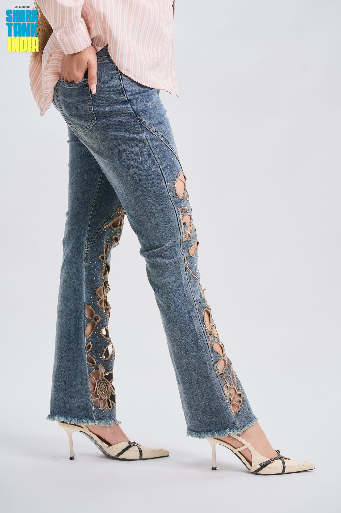 Flared jeans with floral cut-out details on a white background
