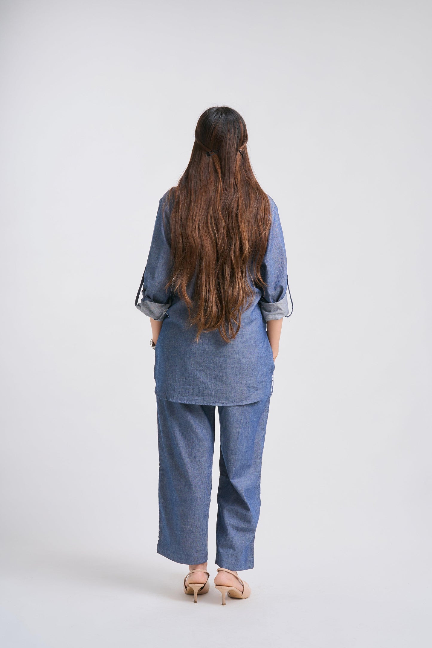 Woman wearing a blue outfit standing against a white background
