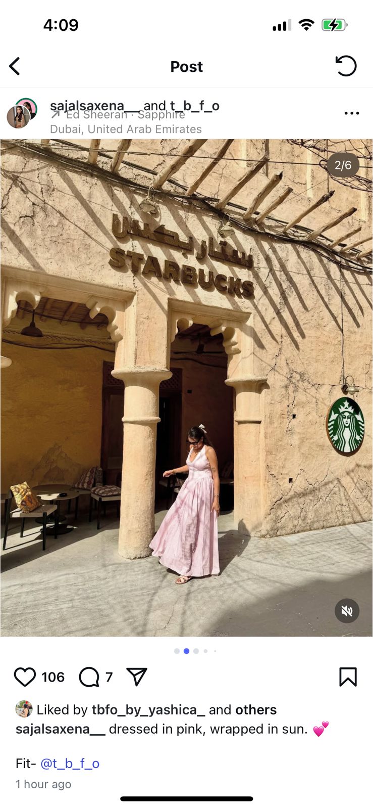 Woman in a pink dress standing in front of a Starbucks location with Arabic script on the building.