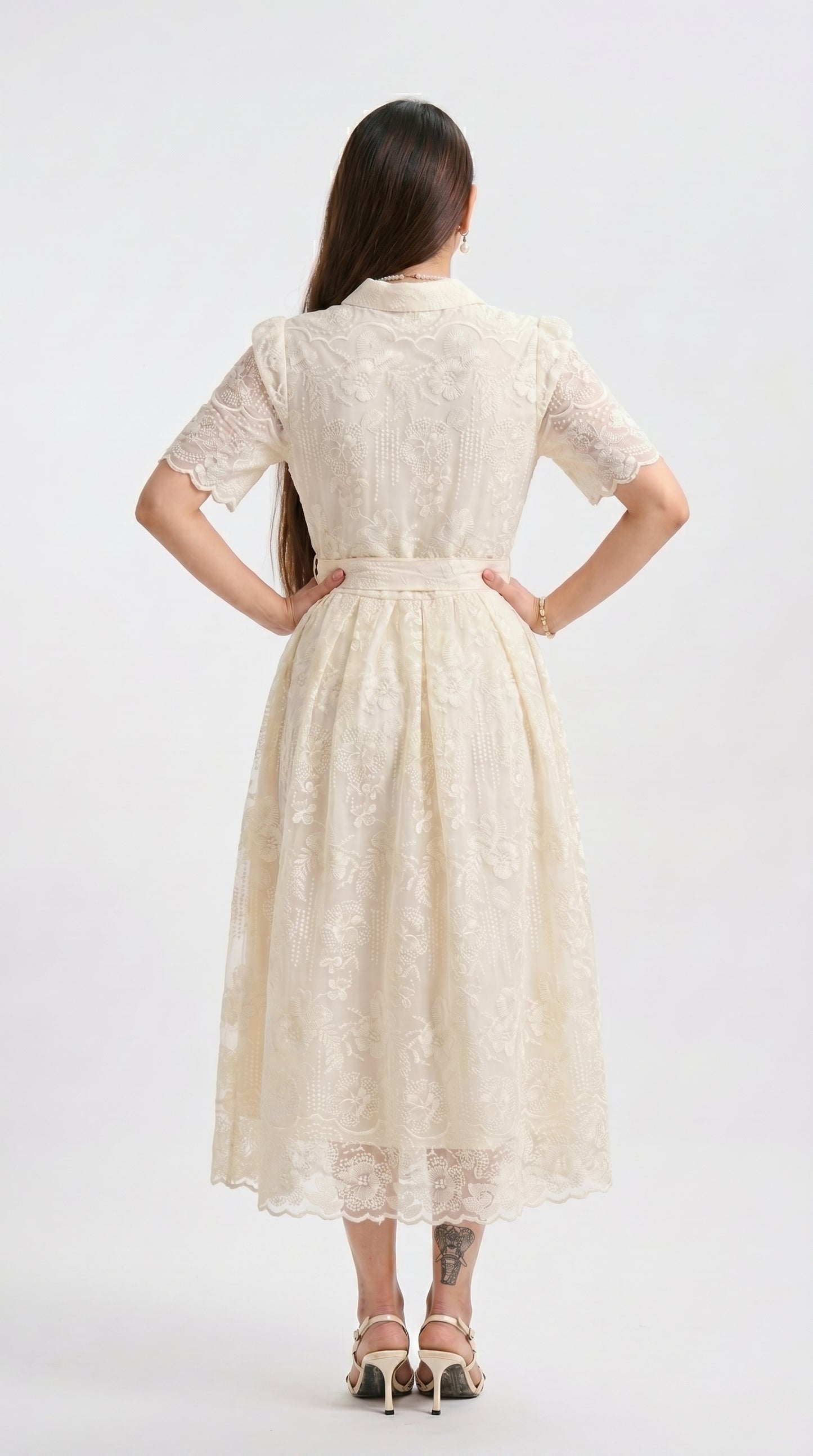 Woman wearing a beige lace dress on a white background