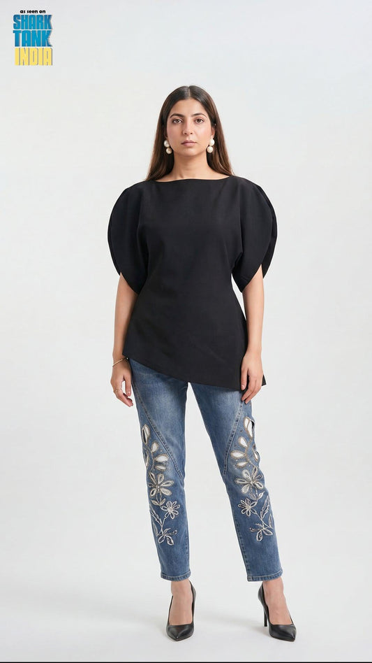 Woman wearing a black top and blue jeans with floral embroidery on a white background