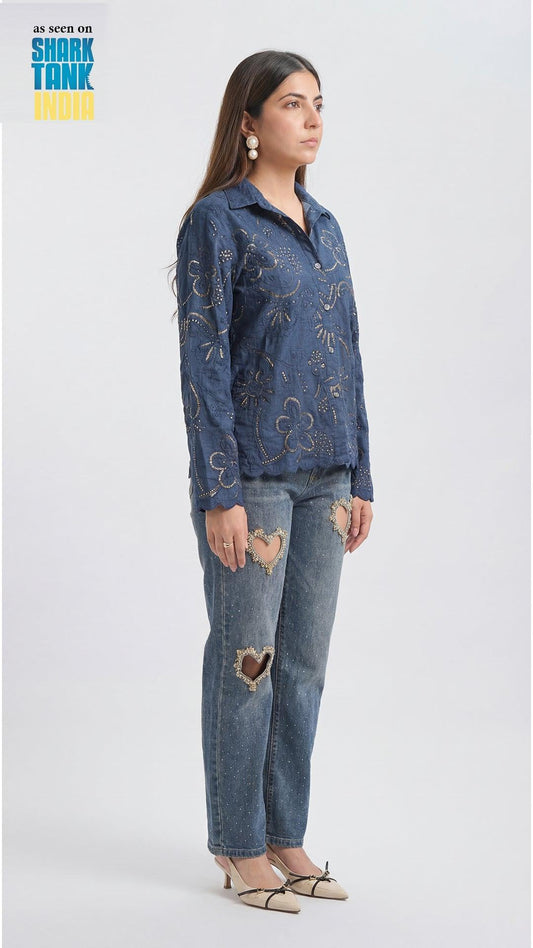 Woman wearing a blue patterned top and jeans on a white background