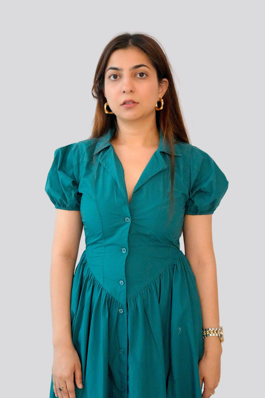 Woman wearing a teal dress against a plain background
