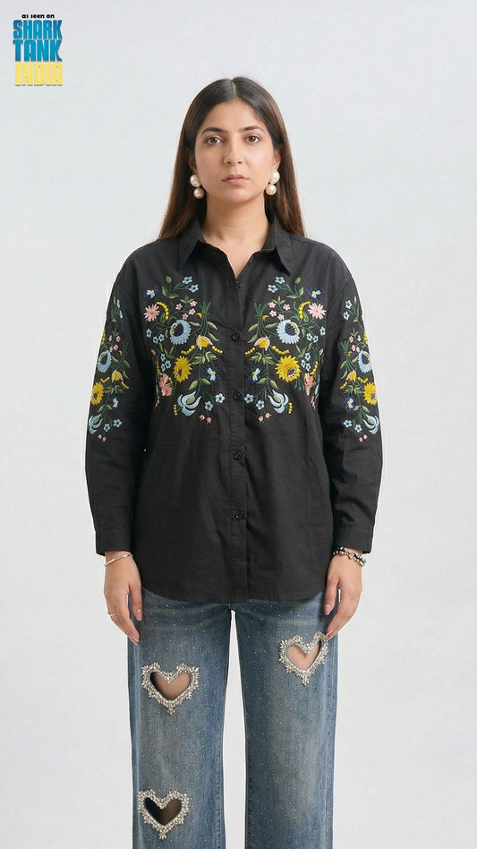 Woman wearing a black embroidered shirt and jeans on a white background