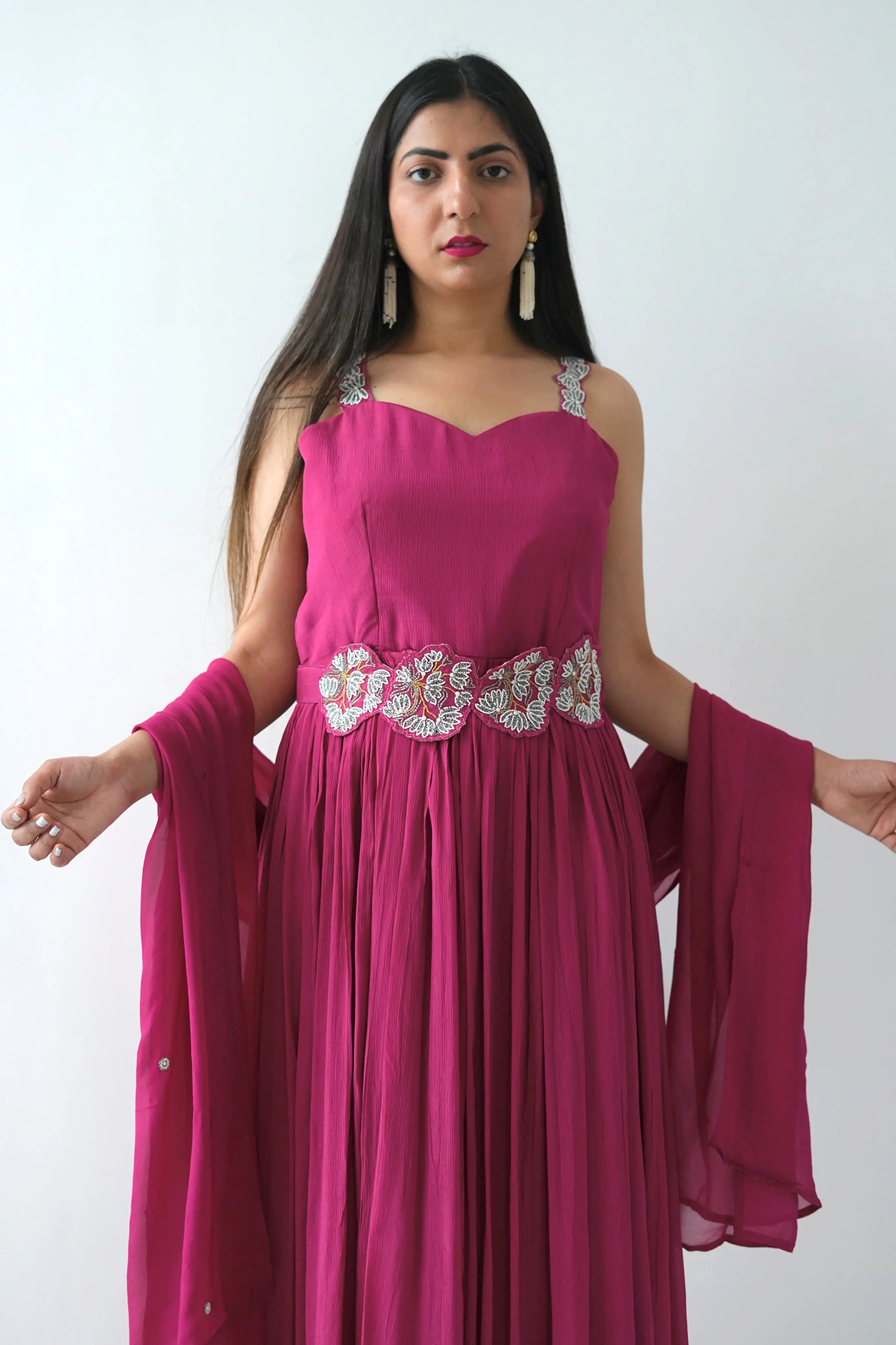 Woman wearing a pink dress with embellishments on a white background