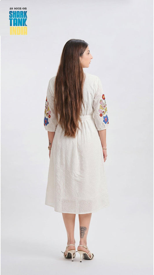 Woman wearing a white dress with floral embroidery on a white background