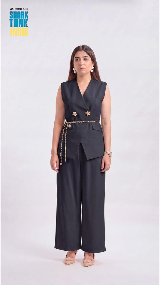 Woman wearing a black sleeveless blazer and wide-leg pants on a white background with 'Shark Tank India' branding.