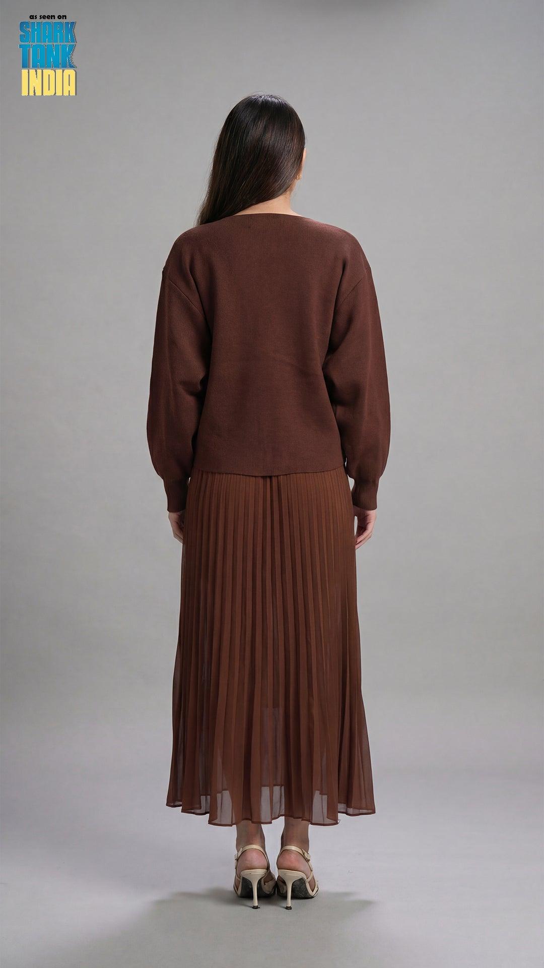 Woman wearing a brown outfit with a pleated skirt on a gray background