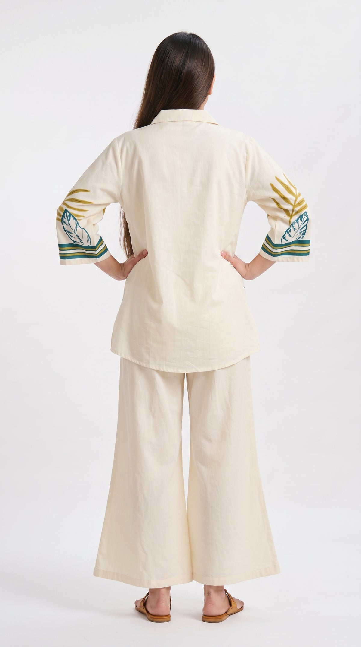 Woman wearing a beige outfit with embroidered sleeves on a white background