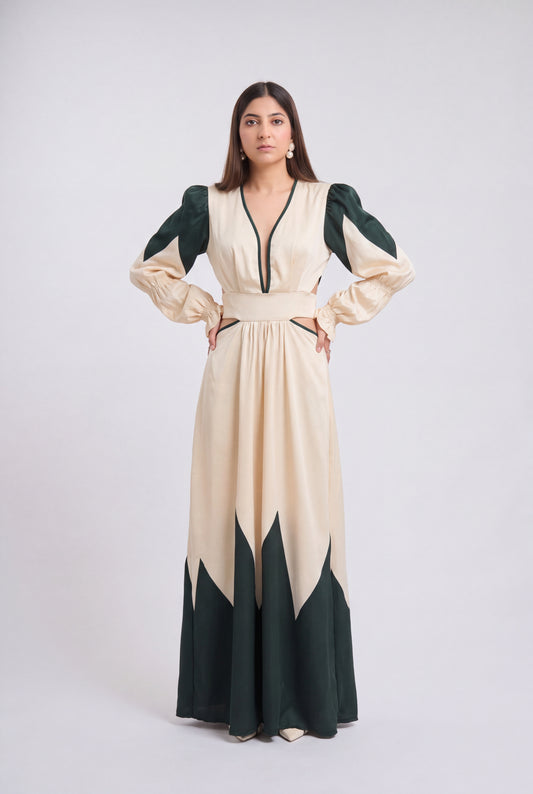 A woman modeling a long cream maxi dress with dark green color-blocked sleeves, neckline trim, and hem details, standing against a light gray studio background.