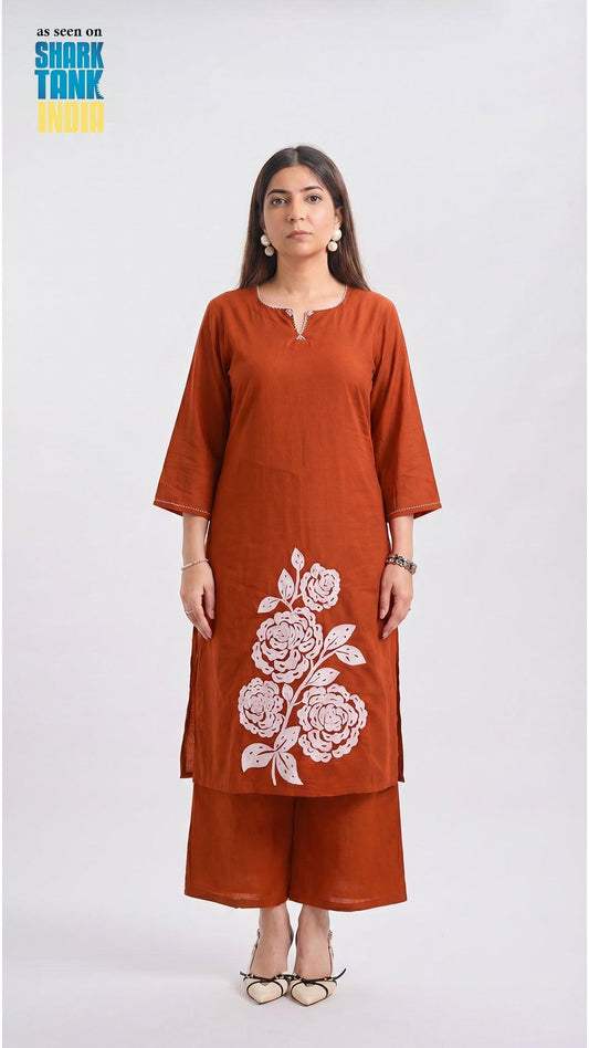 Woman wearing a rust-colored kurta with floral embroidery on a white background