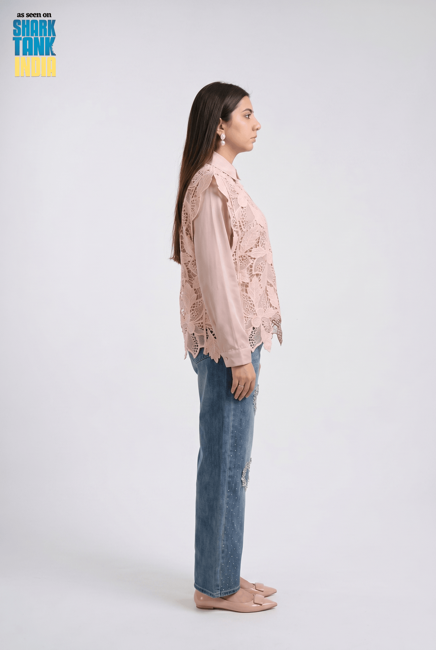 Woman wearing a pink lace blouse and blue jeans on a white background with 'Shark Tank' branding.