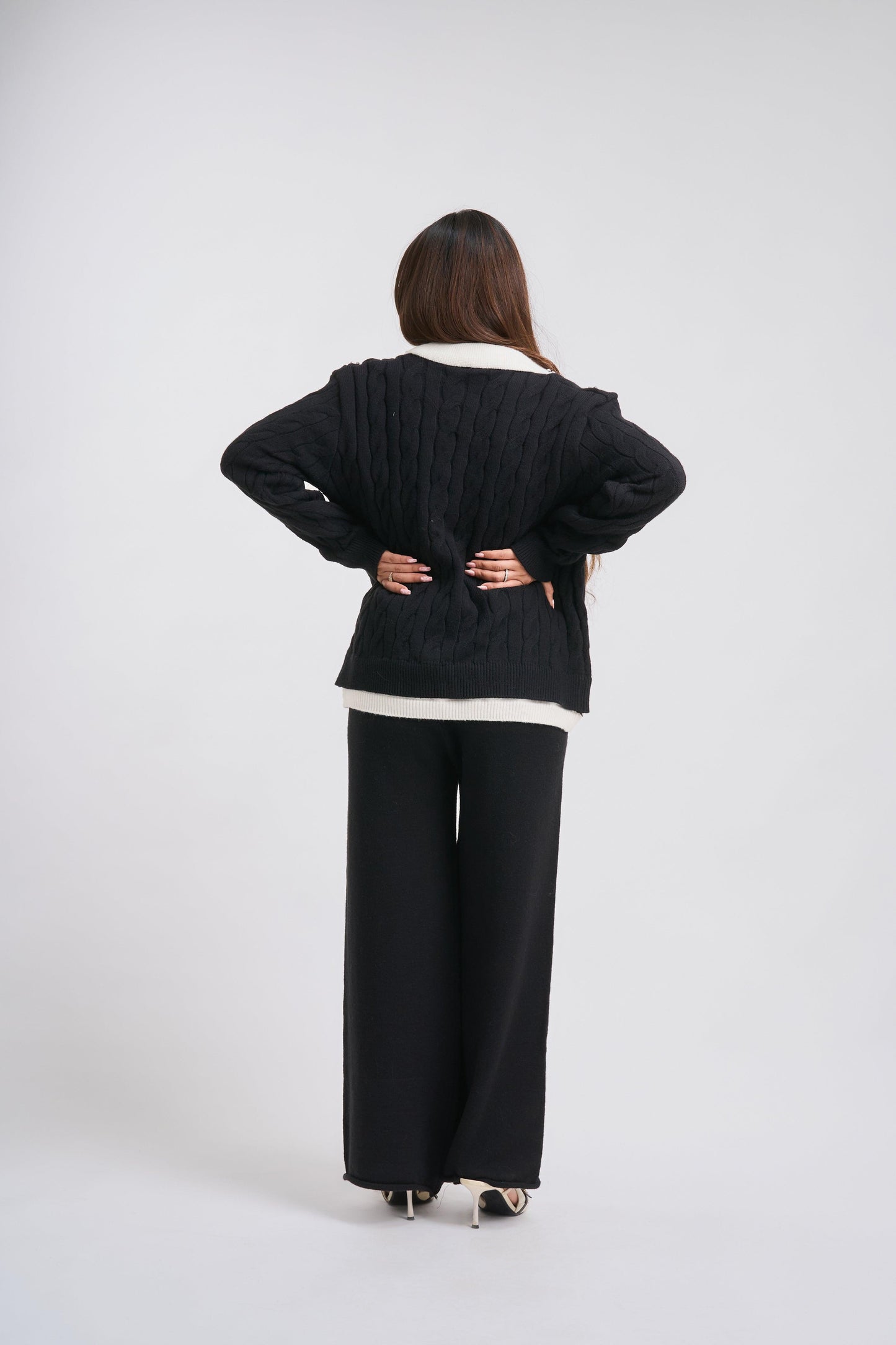 Person wearing a black outfit with a white shirt on a plain background