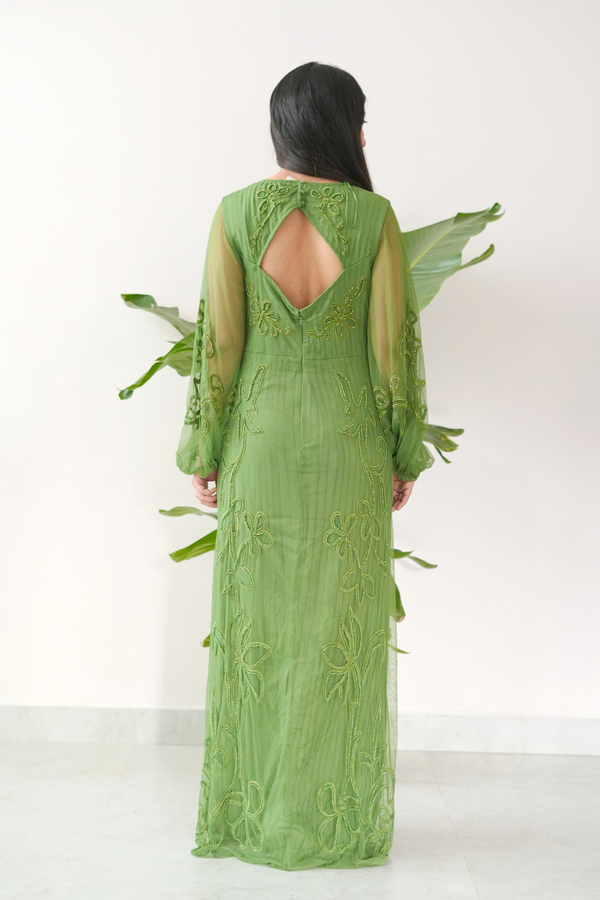 Green embroidered dress with open back and leaf-like accessories on a white background