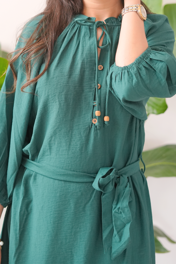 Green dress with long sleeves and a belt, worn by a person.