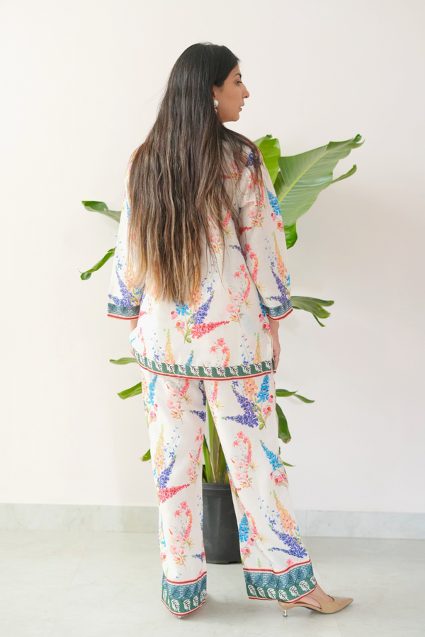 Woman wearing a colorful pajama set with a white background and plant decor.
