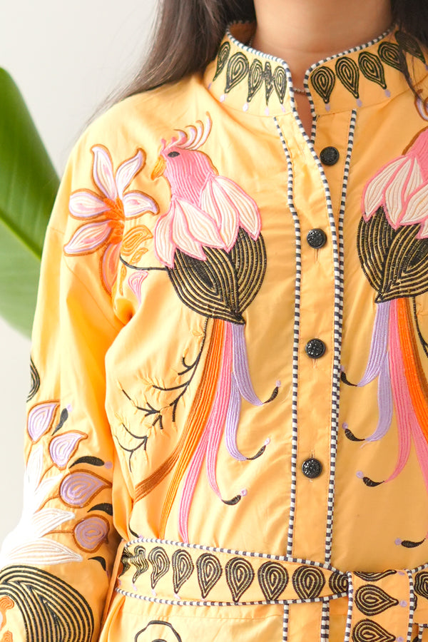 Yellow outfit with floral embroidery on a neutral background