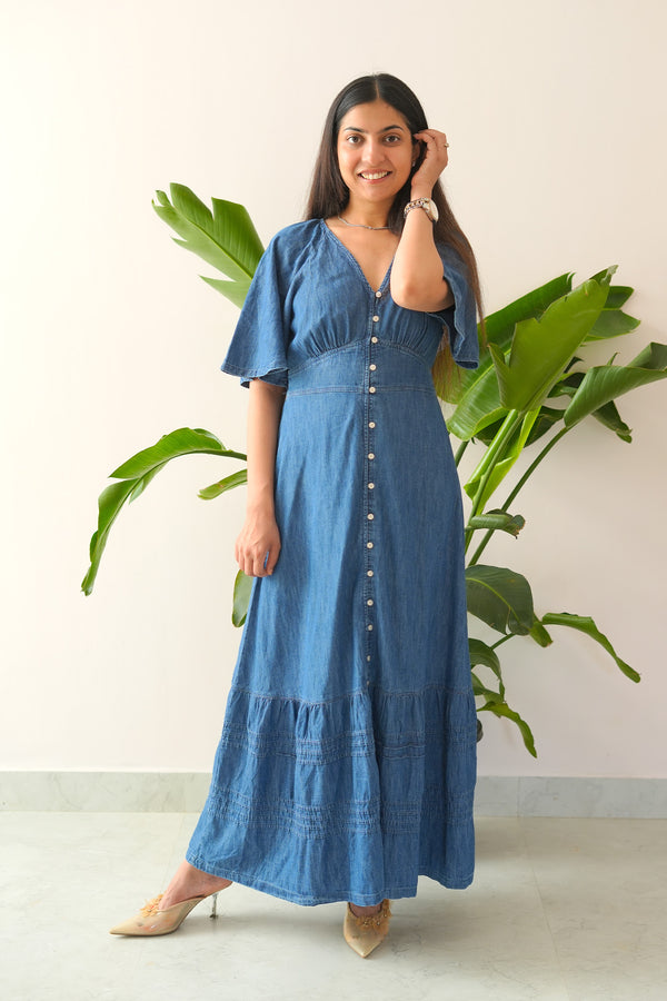 Woman wearing a blue dress standing in front of a plant