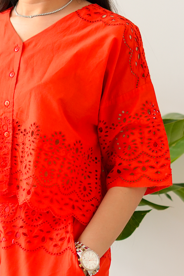 Red kurta with intricate cut-out patterns worn by a person, with a blurred background.